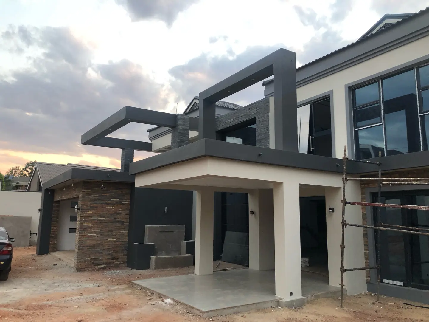 Exterior finishing Harare — modern two-storey residence with completed paint and stone cladding at dusk