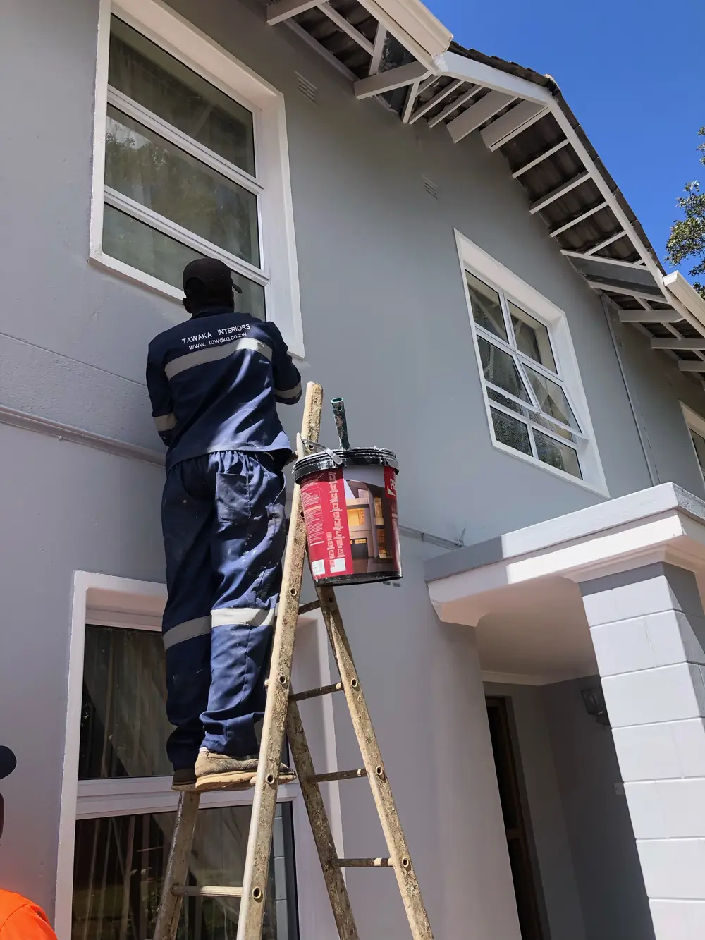 Exterior painting Harare — Tawaka Contracting painter in branded workwear cutting in trim on a Highlands home